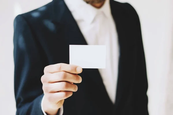 Businessman giving a blank white business card.Horizontal mockup, blurred background. — Stock Photo, Image