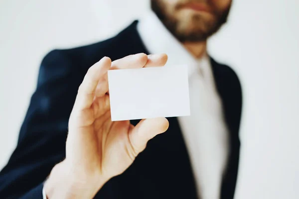 Empresario mostrando una tarjeta de visita blanca limpia.Simulación horizontal, fondo borroso . — Foto de Stock