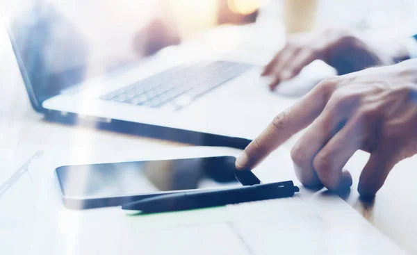 Nahaufnahme eines Mannes, der im Büro an einem modernen Mobiltelefon arbeitet und mit dem Finger auf die Home-Taste des Smartphones zeigt. Horizontaler, verschwommener Hintergrund, visuelle Effekte. — Stockfoto