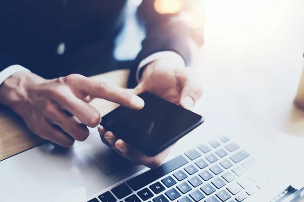 Man arbetar på moderna mobiltelefon på soliga kontor och rör finger till hemknappen av smartphone. Horisontell, suddig bakgrund, visuella effekter. — Stockfoto