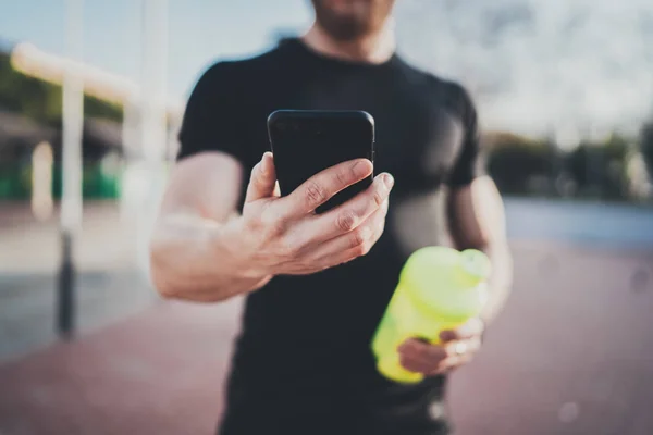 Smart workout session concept.young muscular Athlet check training program on smartphone application after perfect workout session at sunny morning.unscharfer Hintergrund. — Stockfoto