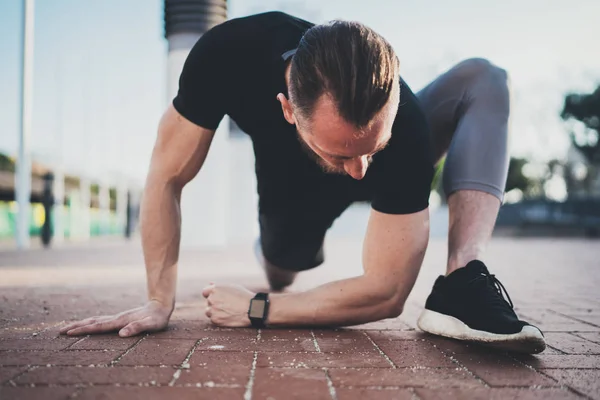 Concepção de estilo de vida.Jovem fazendo exercícios de alongamento músculos antes do treinamento.Atleta muscular exercitando-se fora no parque ensolarado. Fundo desfocado . — Fotografia de Stock