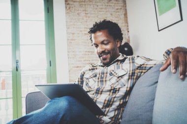 Evdeki kanepede oturan adam.