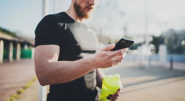 Atleta jovem muscular verificando calorias queimadas no aplicativo smartphone após uma boa sessão de treino ao ar livre no parque ensolarado.Fundo borrado. . — Fotografia de Stock