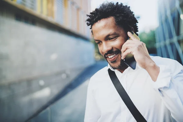 Retrato de hombre africano americano feliz usando el teléfono inteligente para llamar a amigos en la calle soleada.Concepto de jóvenes felices disfrutando de gadgets al aire libre.Fondo borroso . — Foto de Stock