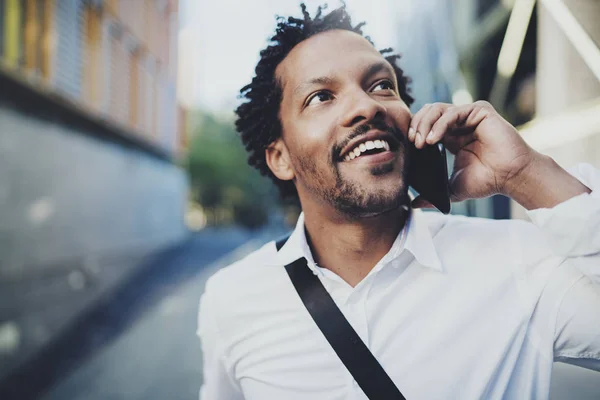 Retrato de hombre negro africano americano feliz usando el teléfono móvil para llamar a amigos en la calle soleada.Concepto de jóvenes felices disfrutando de gadgets exteriores.Fondo borroso . — Foto de Stock