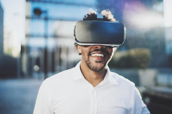 Concept of technology,gaming,entertainment and young people.Smiling american african man enjoying virtual reality glasses or 3d spectacles.Blurred background.Horizontal. — Stock Photo, Image