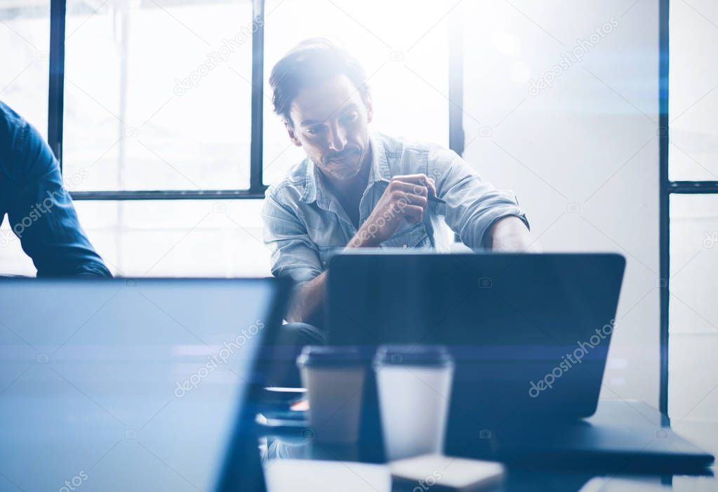 Adult handsome businessman working on mobile computer at sunny office.Coworker typing on notebook keyboard.Horizontal.Blurred background.