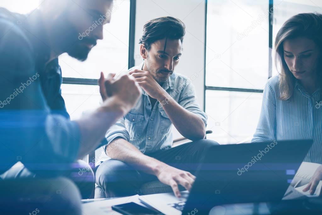 Group of young coworkers discussing ideas with each other in modern office.Business people using electronic devices.Horizontal, blurred background.