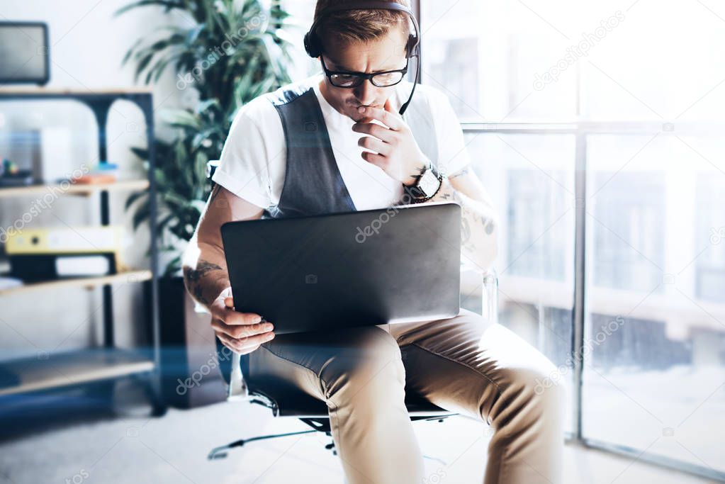 Businessman working on his digital tablet holding in hands. Elegant man wearing audio headset and making video conversation via digital tablet.Blurred background.