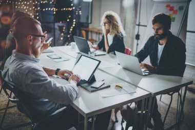 Grup genç iş modern coworking studio birlikte çalışır. Muhabbet ortakları ile masada gençler. Horizontal.Blurred arka plan.