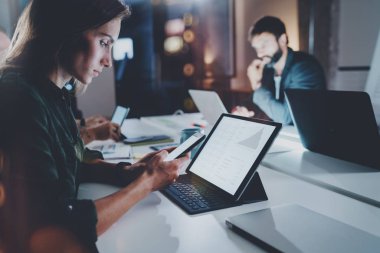 Çalışma arkadaşları fotoğraf işlemek. Genç kız gece modern ofis çatı katında birlikte meslektaşları ile çalışma. Ekip çalışması kavramı. Arka plan bulanık. Yatay.