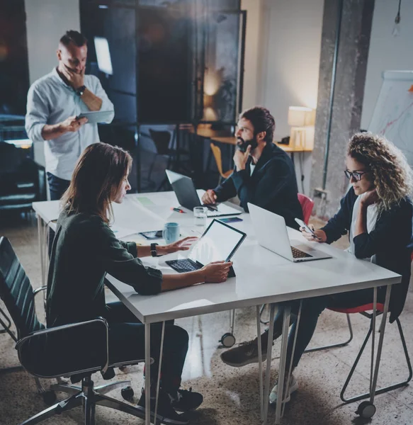 Skupina mladých spolupracovníků spolupracují moderní coworking studio. Mladí lidé dělat rozhovor s partnery u stolu. Horizontal.Blurred pozadí. Náměstí. — Stock fotografie