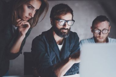 Genç arkadaşları birlikte modern coworking Studio dizüstü bilgisayarlarda geceleri çalışma grubu. Dizüstü bilgisayar kullanarak gözlüklü adam. Horizontal.Blurred arka plan. Kırpılmış.