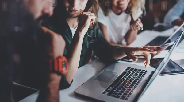 Молодая женщина указывает на ноутбук display.Team молодых сотрудников работать вместе в ночном офисе. Horizontal.Blurred фон . — стоковое фото
