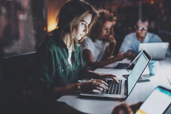 Team junger Mitarbeiter, die nachts im Büro zusammenarbeiten.junge Frau mit mobilem Laptop am Tisch.horizontal.verschwommener Hintergrund. — Stockfoto