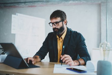 Genç erkek mimar onun masasında bir dijital tablet rıhtım üzerinde göz gözlük takan sakallı. Profesyonel deneyimli mühendis constructionist geliştirici kavramı. Horizontal.Blurred arka plan.