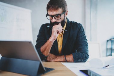 Onun masasında bir dijital tablet rıhtım üzerinde göz gözlük takan dalgın sakallı erkek mimar. Profesyonel deneyimli mühendis constructionist geliştirici. Horizontal.Blurred arka plan.