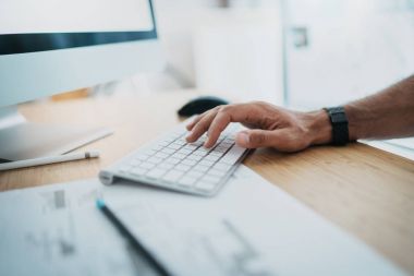 Erkek el bilgisayar klavyede yazarak. Blogger tahta masada otururken stüdyoda çalışıyor. Horizontal.Blurred arka plan.
