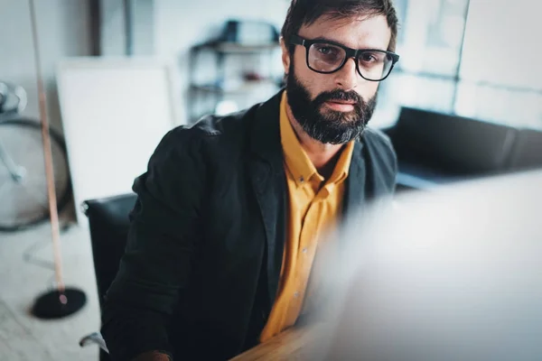 Closeup view of Young bearded designer using laptop computer at modern coworking studio.Panoramic windows on blurred background.Horizontal. — Stock Photo, Image