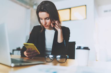 Ofiste çalışırken Smartphone'da kısa mesaj yazarak çekici iş kadını. Arka plan bulanık.