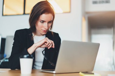 Dalgın güzel iş kadını modern ofis dizüstü bilgisayar kullanarak. Arka plan bulanık. Yatay.