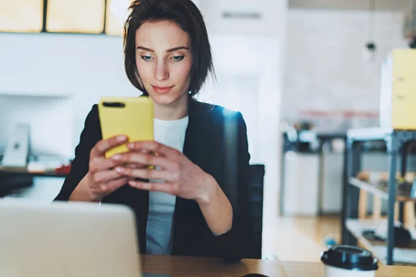 Zakenvrouw gebruiken smartphone terwijl u werkt op kantoor. Onscherpe achtergrond. — Stockfoto