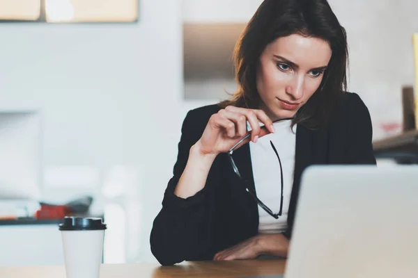 Porträtt av leende vacker affärskvinna använder bärbar dator på moderna kontor. Suddig bakgrund. Horisontell. — Stockfoto