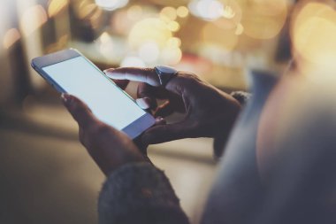 Kız gece atmosferik şehirde ekran smartphone cep telefonu ile işaret parmağı. Eller manifatura mesaj cep telefonu. Portre üzerinde arka plan bulanık. İşaret fişekleri, bokeh etkileri.