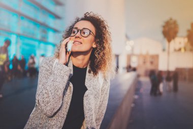 Gülümseyen kadın gece sokakta duran onun hücre telefon ile mobil telefon görüşmesi. Arka plan bulanık bokeh ve mercek parlamaları etkisi.