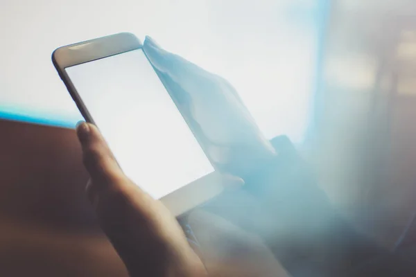 Menina segurando smartphone com tela branca vazia na cidade atmosférica noturna.Fechar-se no fundo embaçado . — Fotografia de Stock