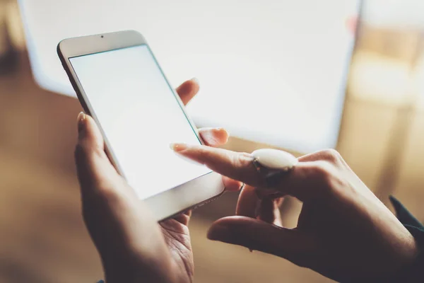 Vrouw aanraken van de vinger op het scherm smartphone in de sfeervolle stad nacht. Vrouwelijke handen SMS bericht mobiele telefoon. Close-up op onscherpe achtergrond. Fakkels, bokeh effecten. — Stockfoto