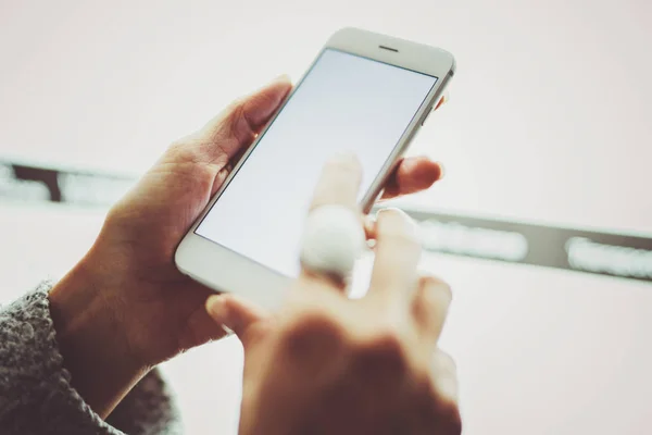 Mädchen zeigt mit dem Finger auf den Bildschirm smartphone.female Hände SMS-Nachricht Mobiltelefon .closeup auf verschwommenem hellen Hintergrund. — Stockfoto