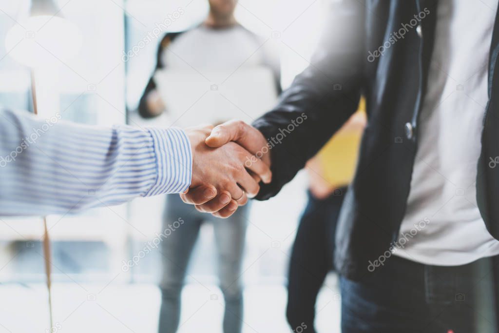 Close up view of business partnership handshake.Concept two coworkers handshaking process.Successful deal after great meeting.Blurred background.