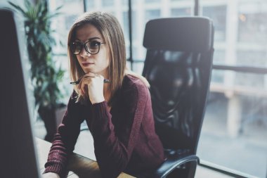 Çekici genç iş kadını ofiste modern çalışma yerde masaüstü bilgisayar kullanarak. Arka plan bulanık. Yatay.