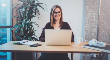 Gece ofiste iş işlemi sırasında yeni bir iş çözüm arayanlar için mobil dizüstü bilgisayar kullanan genç mutlu kız. Arka plan bulanık.