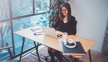 Ortakları ile iş görüşmesinde gece ofiste iş işlem yapmak için mobil dizüstü bilgisayar kullanan mutlu genç kadın. Arka plan bulanık.