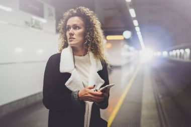 Gidip transit tren istasyonunda duran smartphone kullanarak üzerinde güzel bir kadın. Çekici kız mutlu konuşma tatil seyahat için cep telefonu app kullanarak.