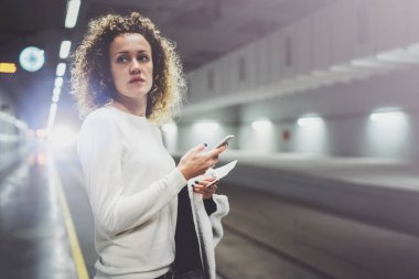 Gidip transit tren istasyonunda duran smartphone kullanarak üzerinde güzel bir kadın. Çekici kız mutlu konuşma tatil seyahat için cep telefonu app kullanarak.