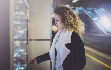 Modern İçecek Otomatı kullanarak transit platform üzerinde çekici bir kadın. Elini çevir rampasında yer alıyor ve küçük görüntü ekranda arıyor.