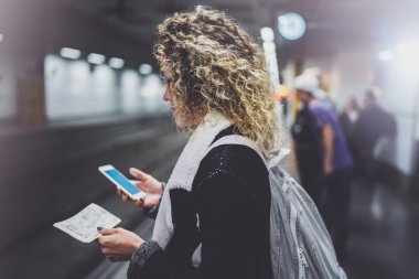 Sırt çantası için smartphone kullanarak transit platformda çekici kadın olun fotoğraf tren bilet metro istasyonu demiryolu tren beklerken.