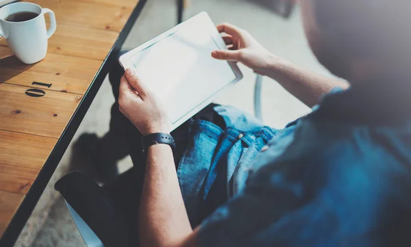 Närbild bild av mannen hålla digital tablett å och använda medan du sitter i fåtölj på coworking plats. Pekande hand Tablet PC-skärmen. — Stockfoto