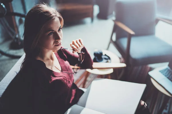 Handsome young girl wearing glasses casual clothes holding book hands.Woman blonde sitting in vintage armchair modern loft studio reading book. Blurred background.Horizontal. — Stock Photo, Image