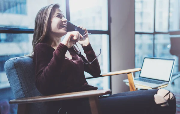 Wanita pengusaha muda yang menarik berbicara dengan mitra melalui telepon modern sambil duduk di kursi yang nyaman di ruang rapat modern . — Stok Foto