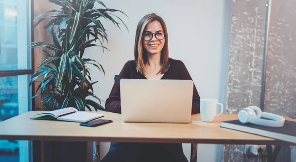 Gece ofiste iş işlemi sırasında yeni bir iş çözüm arayanlar için mobil dizüstü bilgisayar kullanan genç mutlu kız. Arka plan bulanık.