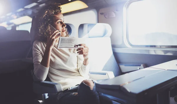 Apreciando o conceito de viagem. Jovem mulher bonita turista viajando pelo trem sentado perto da janela usando smartphone . — Fotografia de Stock