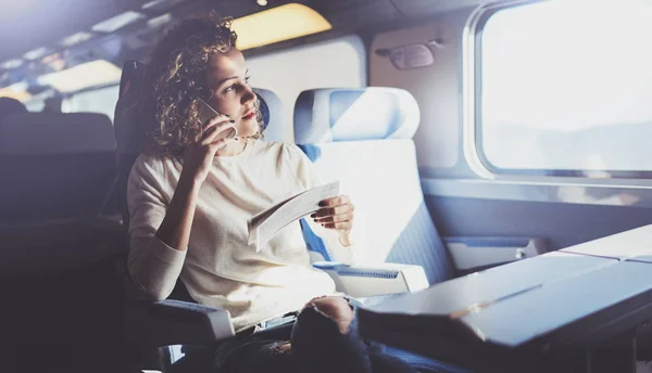 Enjoying travel concept. Young pretty woman tourist traveling by the train sitting near the window using smartphone. — Stock Photo, Image