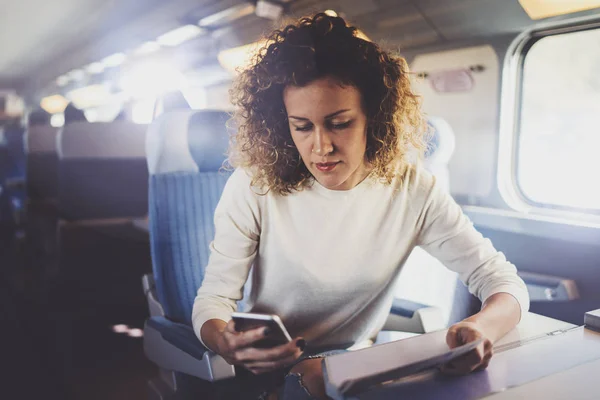 Genieten van reizen concept. Jonge mooie vrouw toeristische reizen met de trein zitten in de buurt van het venster via smartphone. — Stockfoto