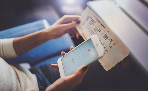 Genieten van reizen bedrijfsconcept. Jonge mooie brunette toeristische meisje op de trein zitten in de buurt van het venster via smartphone, hand in hand ticket. Horizontale closeup. — Stockfoto