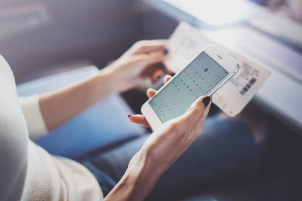 Genieten van reizen bedrijfsconcept. Jonge mooie brunette toeristische meisje op de trein zitten in de buurt van het venster via smartphone, hand in hand ticket. — Stockfoto